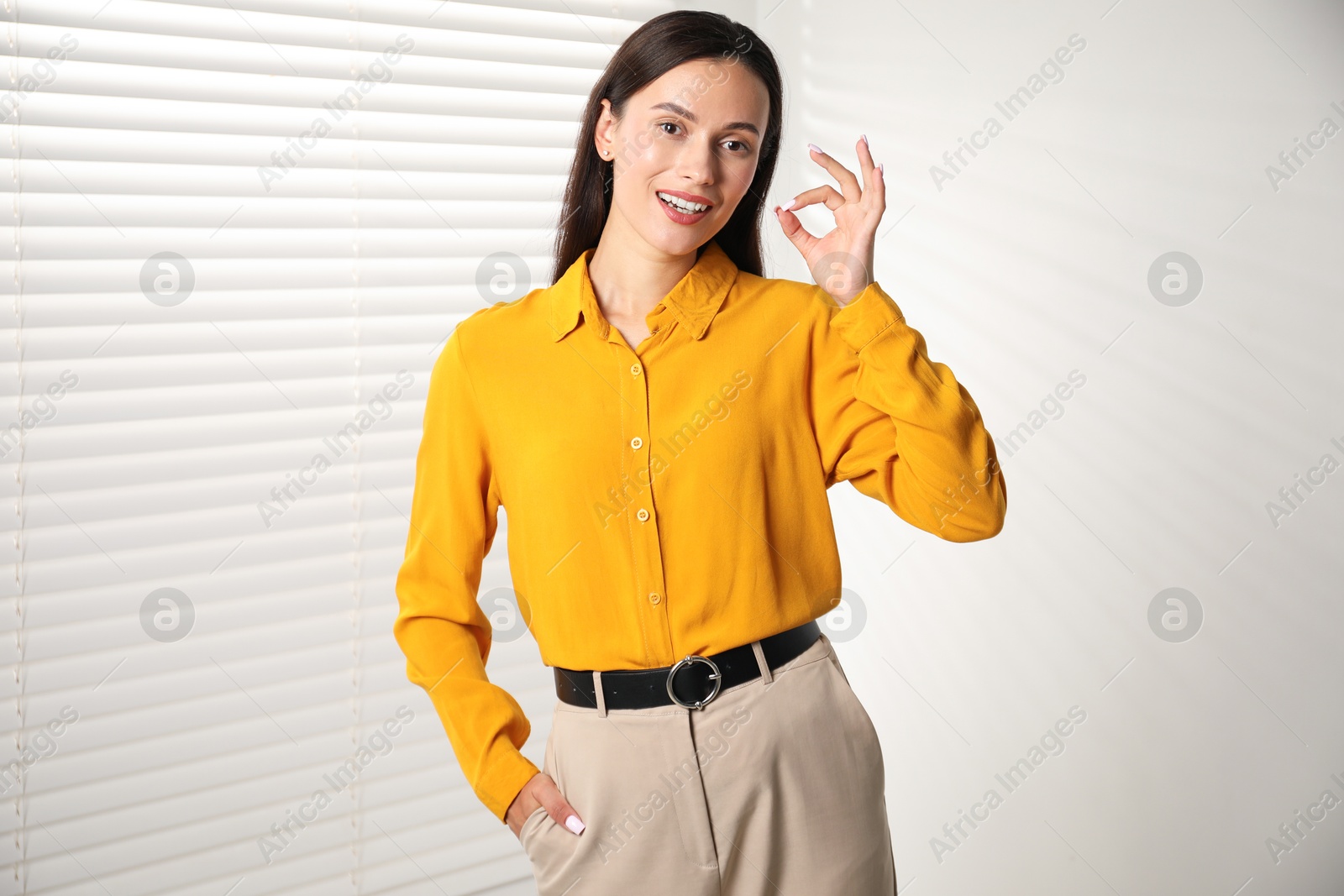 Photo of Beautiful young woman near white wall indoors