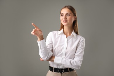 Photo of Businesswoman pointing at something on grey background