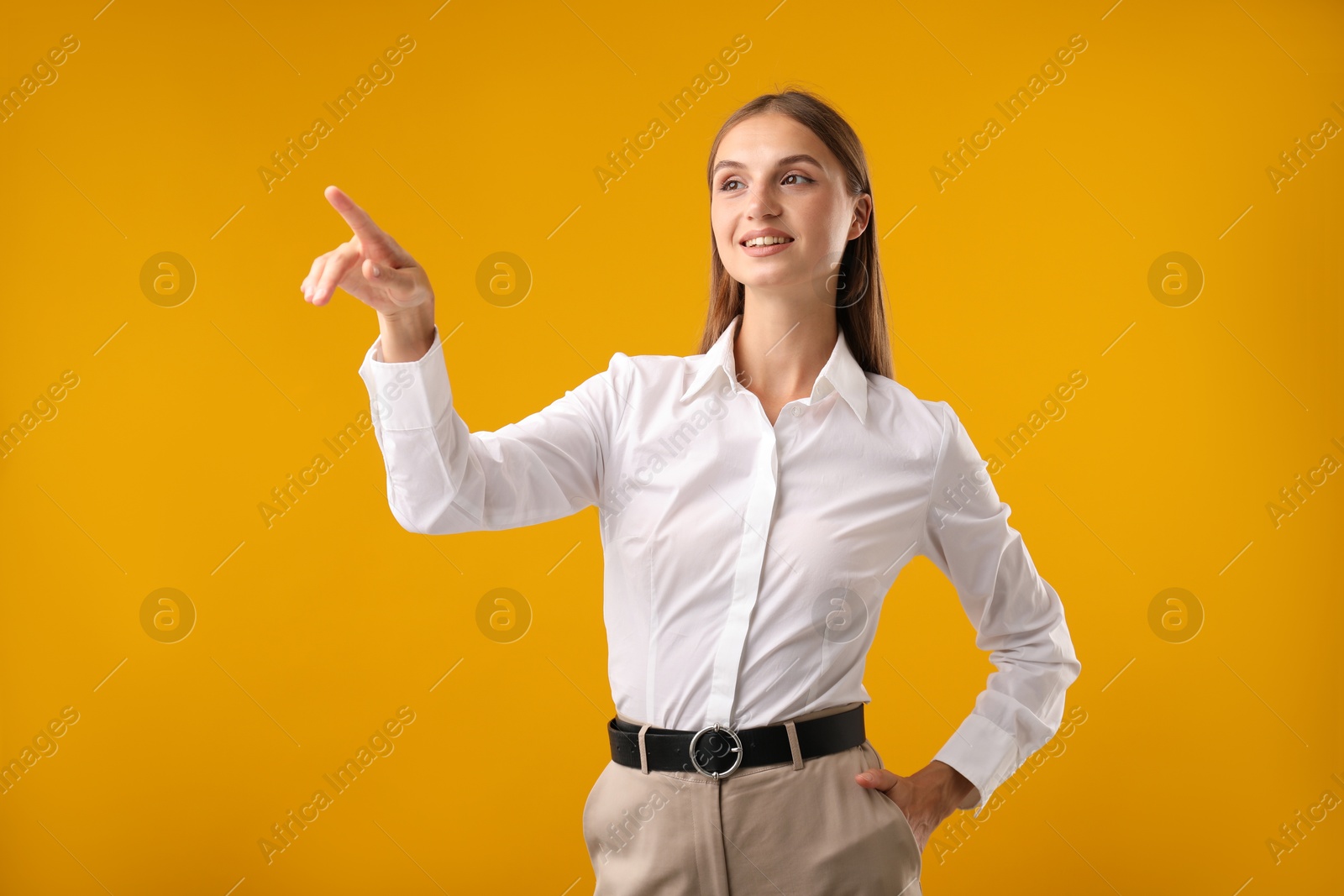 Photo of Beautiful woman pointing at something on yellow background