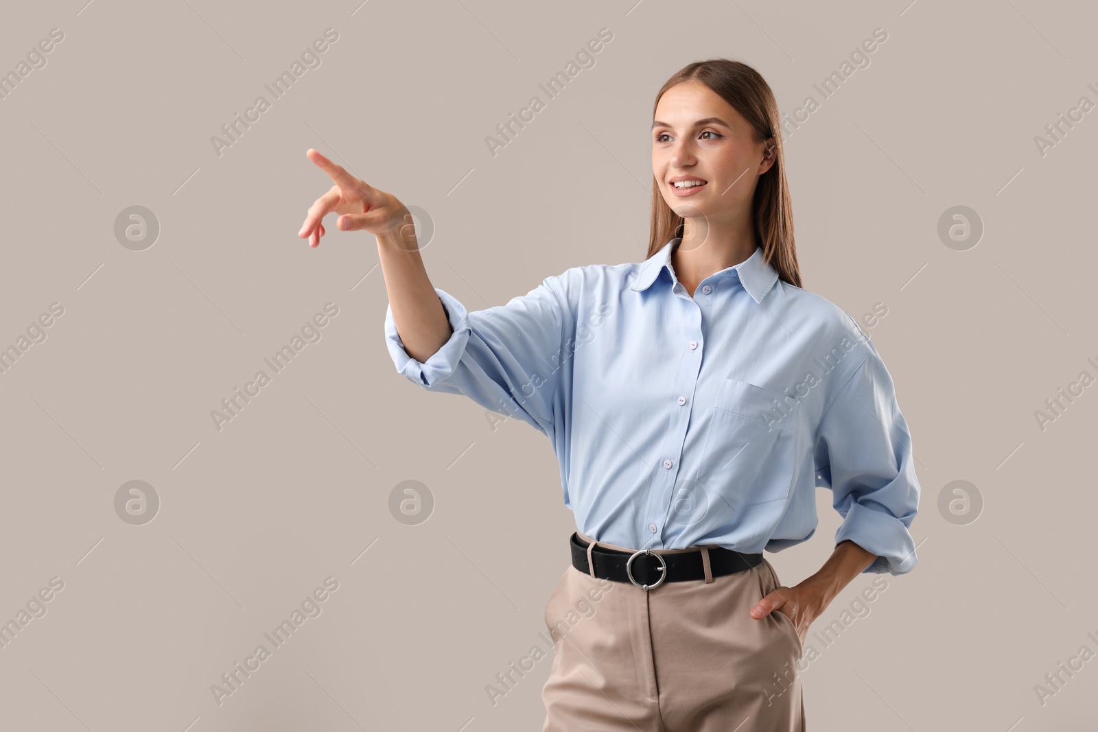 Photo of Beautiful woman pointing at something on light background