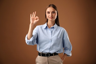Photo of Beautiful woman showing okay gesture on brown background