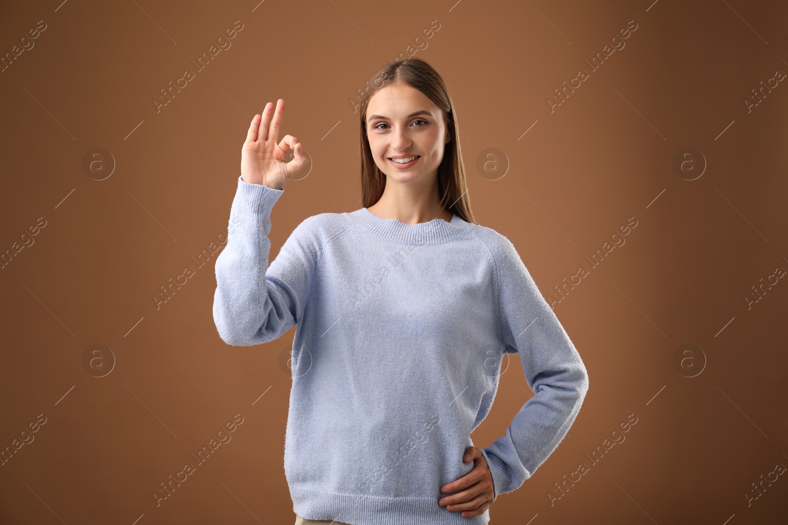 Photo of Beautiful woman showing okay gesture on brown background