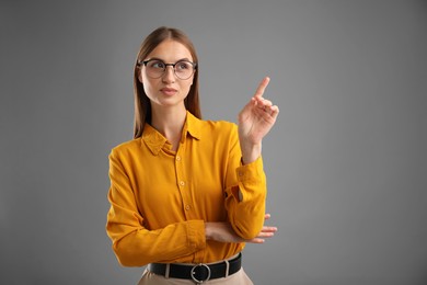 Photo of Confident woman pointing at something on grey background