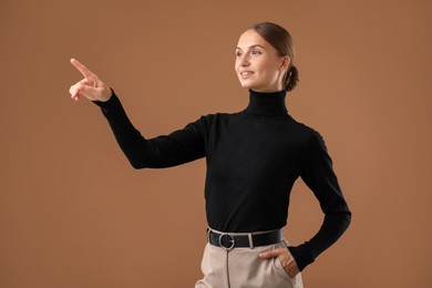 Photo of Beautiful woman pointing at something on brown background