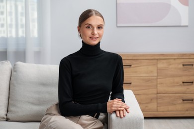 Photo of Elegant woman sitting on sofa at home