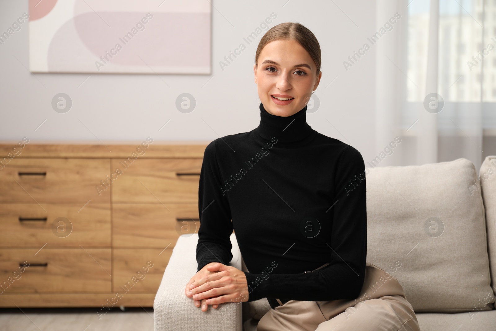 Photo of Elegant woman sitting on sofa at home. Space for text
