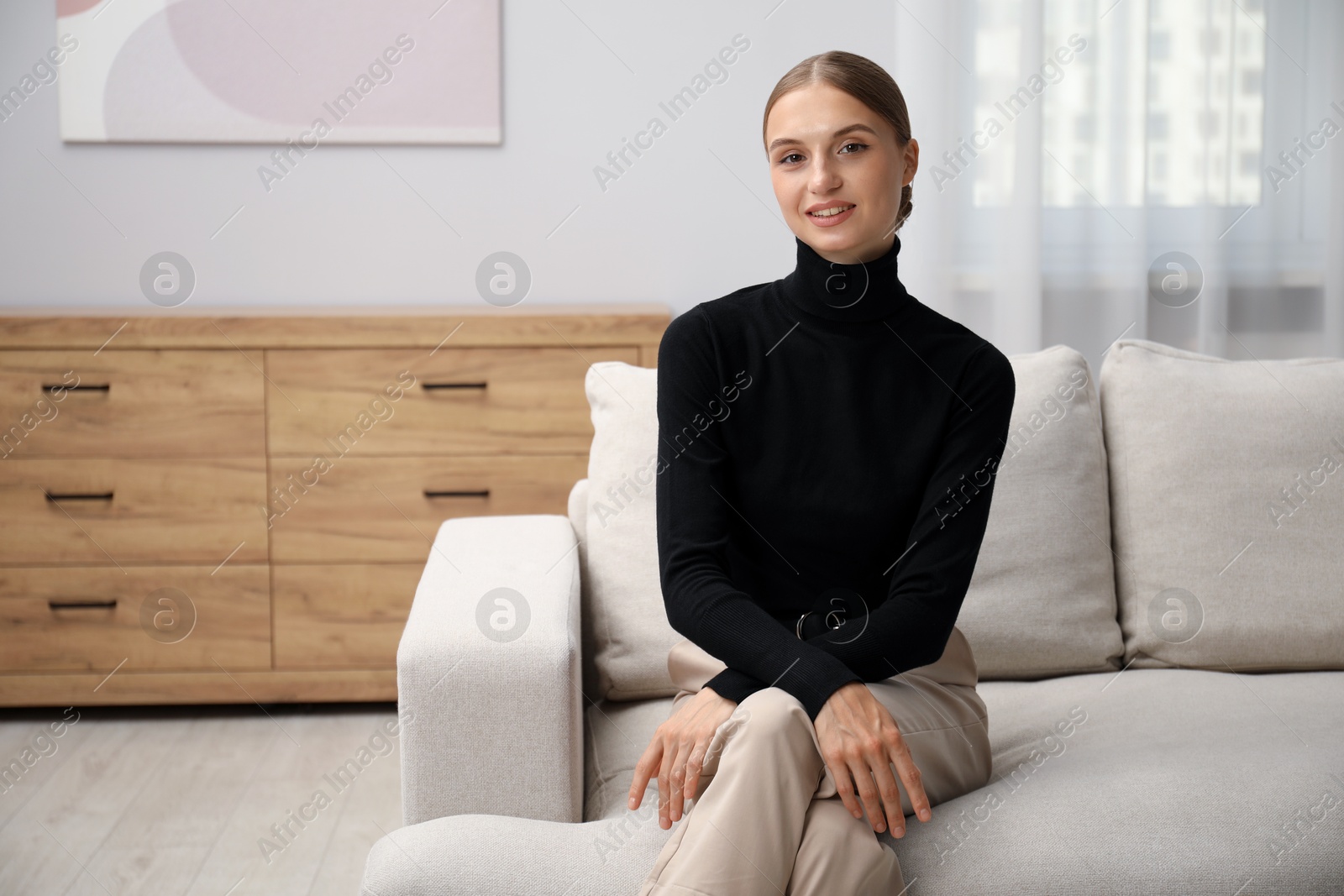 Photo of Elegant woman sitting on sofa at home. Space for text