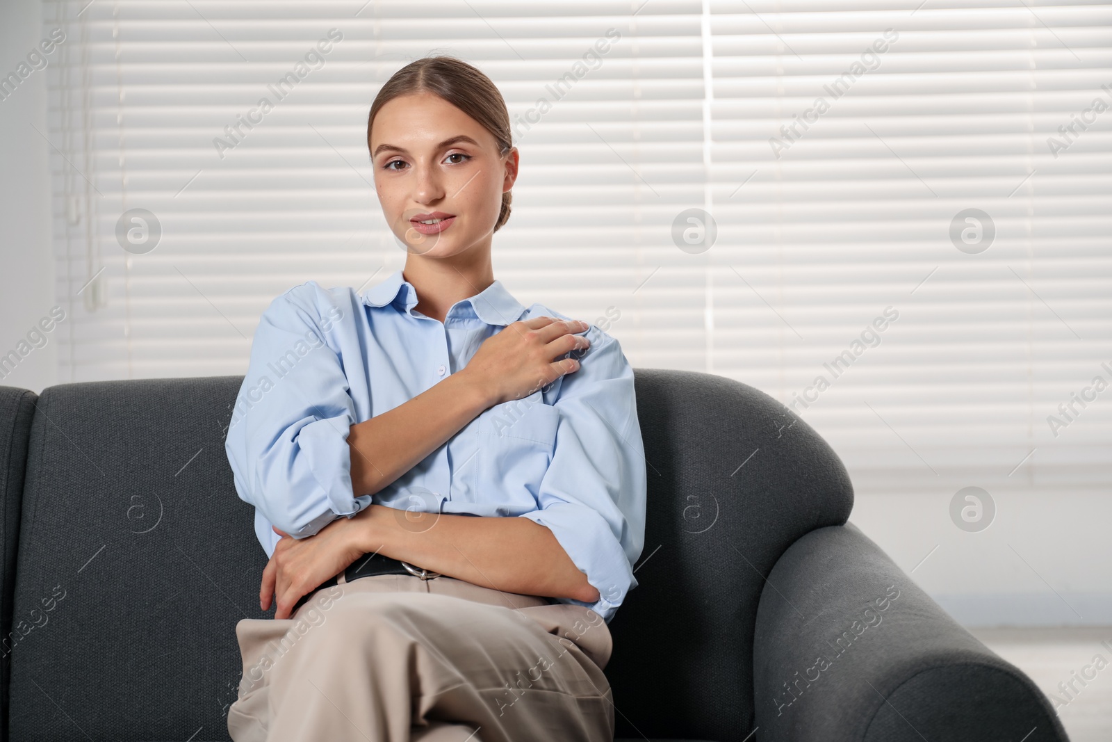 Photo of Beautiful businesswoman sitting on sofa at home. Space for text