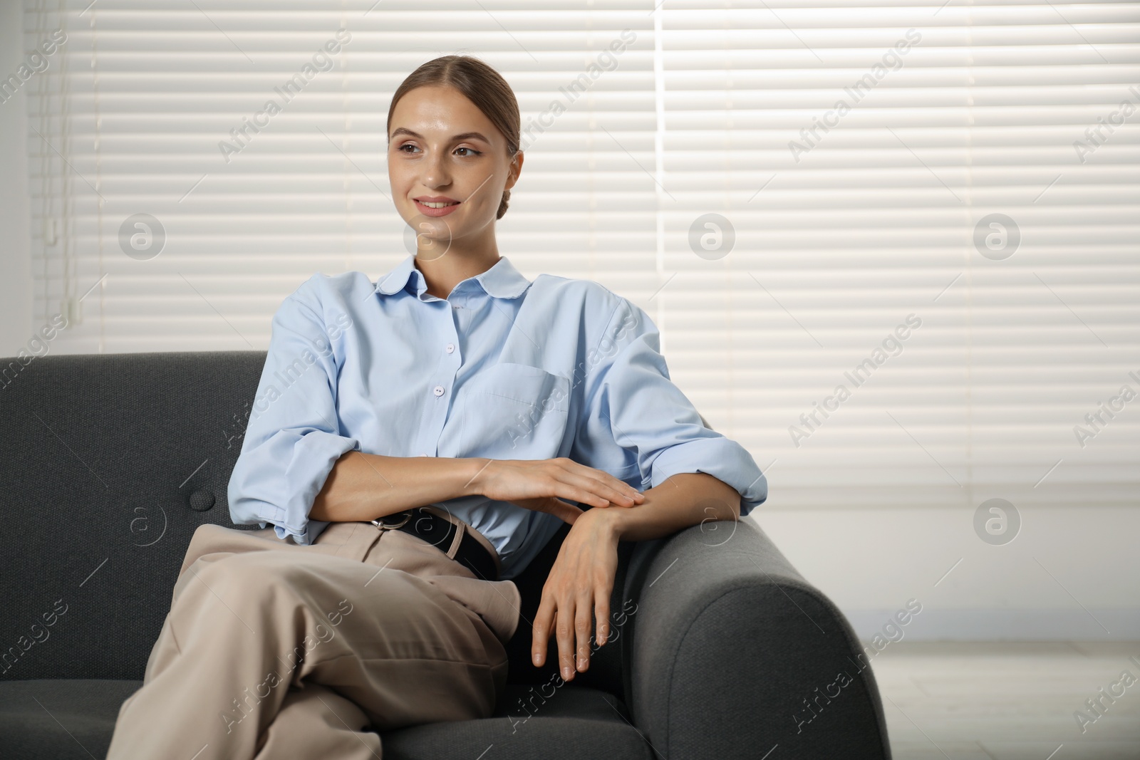 Photo of Beautiful businesswoman sitting on sofa at home. Space for text