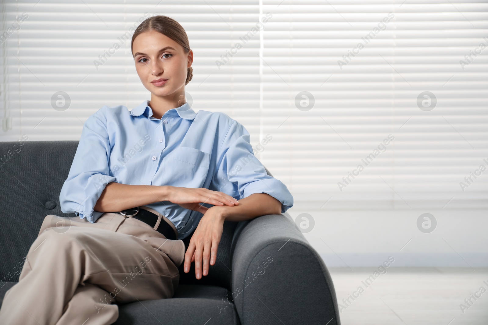 Photo of Beautiful businesswoman sitting on sofa at home. Space for text