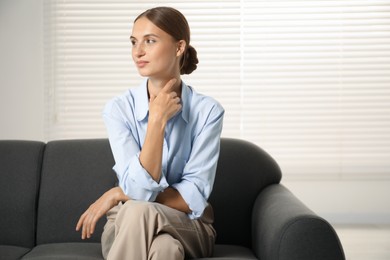 Photo of Beautiful businesswoman sitting on sofa at home. Space for text