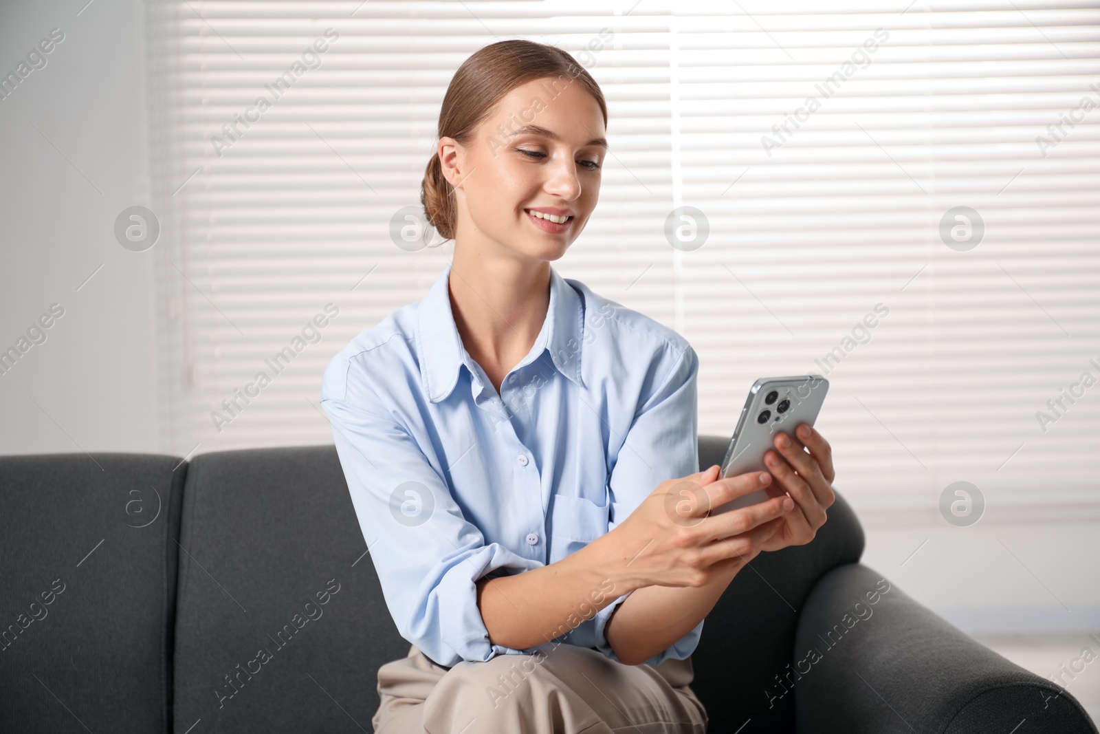 Photo of Beautiful businesswoman with phone on sofa at home