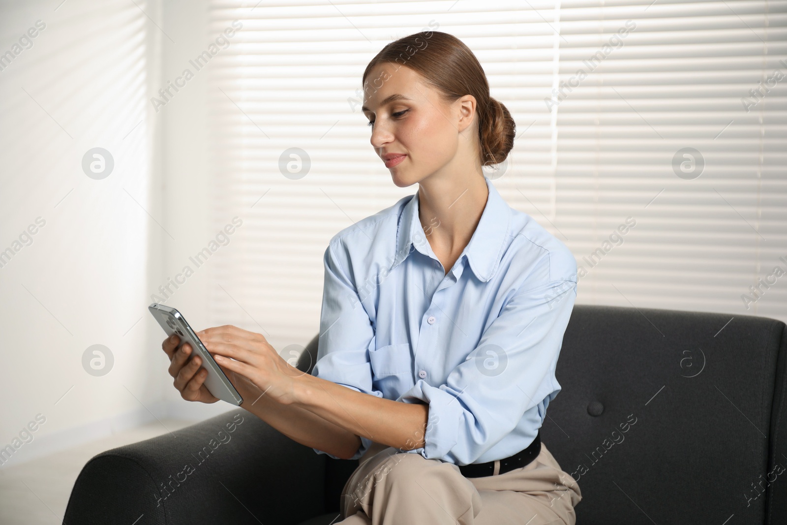 Photo of Beautiful businesswoman with phone on sofa at home