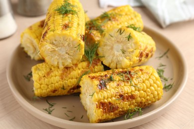 Photo of Pieces of tasty grilled corncobs with dill on wooden table, closeup
