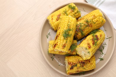 Photo of Pieces of tasty grilled corncobs with dill on wooden table, top view. Space for text