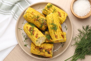 Photo of Pieces of tasty grilled corncobs with dill on wooden table, flat lay