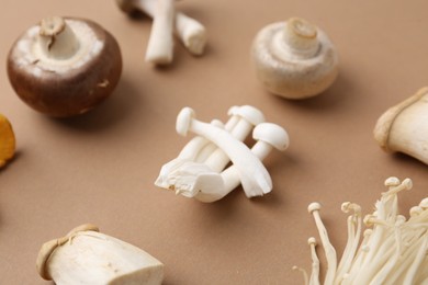 Photo of Different raw mushrooms on beige background, closeup