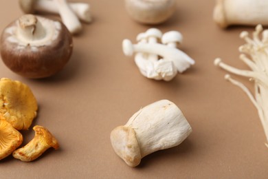 Photo of Different raw mushrooms on beige background, closeup