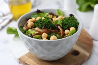 Photo of Delicious salad with shimeji mushrooms, chickpeas and broccoli in bowl on table, closeup