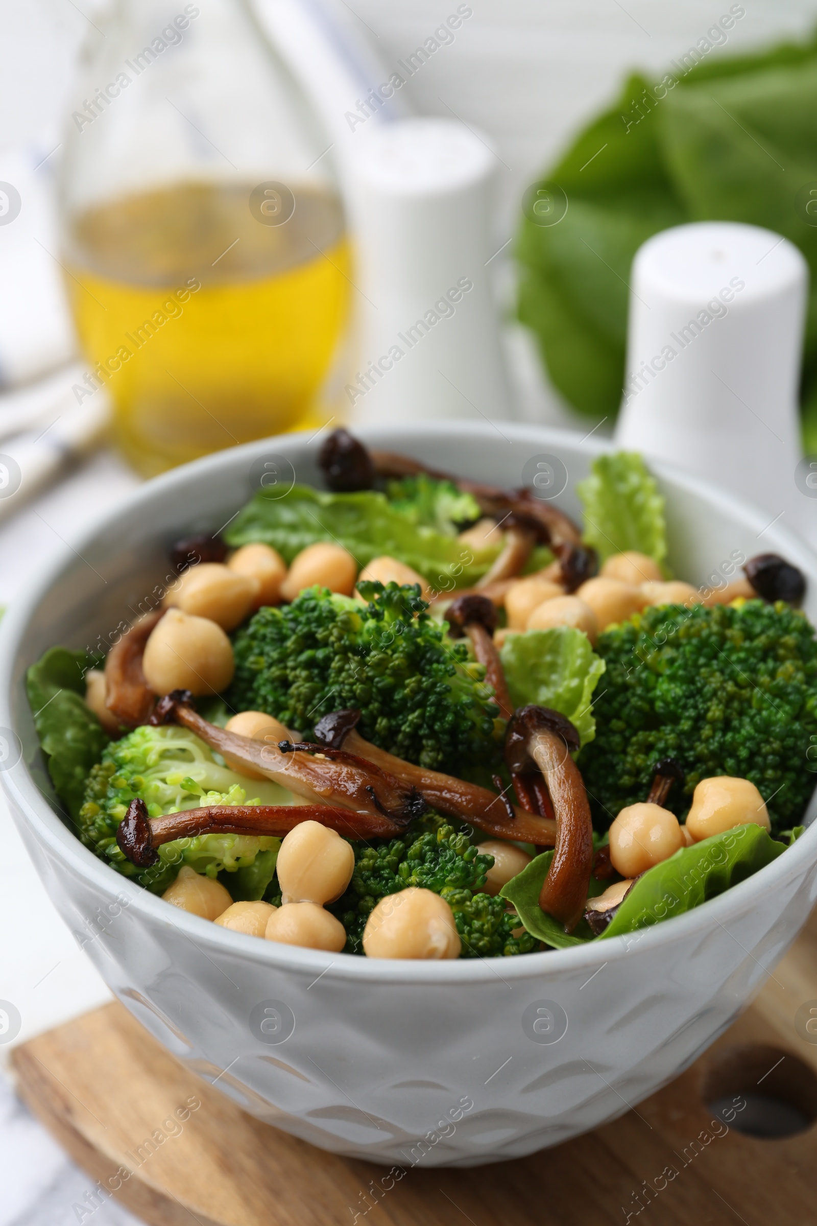 Delicious salad with shimeji mushrooms, chickpeas and broccoli in bowl on table, closeup Photo of Delicious salad with shimeji mushrooms, chickpeas and broccoli in bowl on table, closeup