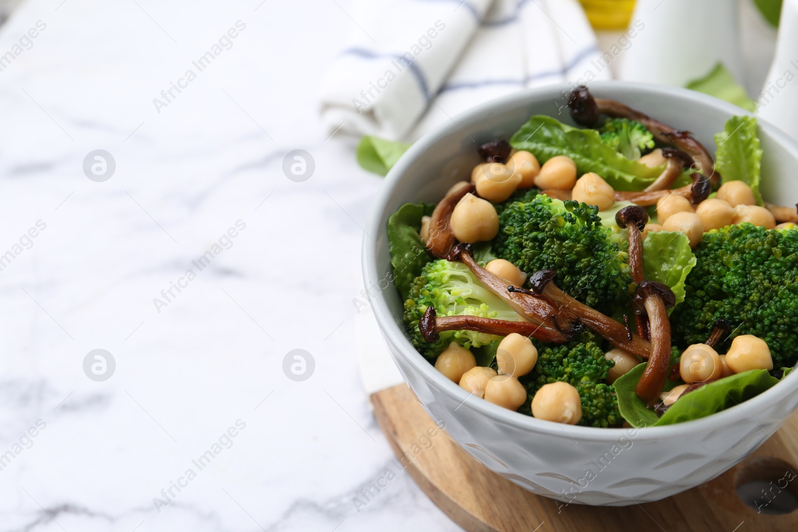 Delicious salad with shimeji mushrooms, chickpeas and broccoli in bowl on white marble table, closeup. Space for text Photo of Delicious salad with shimeji mushrooms, chickpeas and broccoli in bowl on white marble table, closeup. Space for text