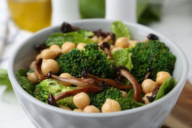 Photo of Delicious salad with shimeji mushrooms, chickpeas and broccoli in bowl on table, closeup