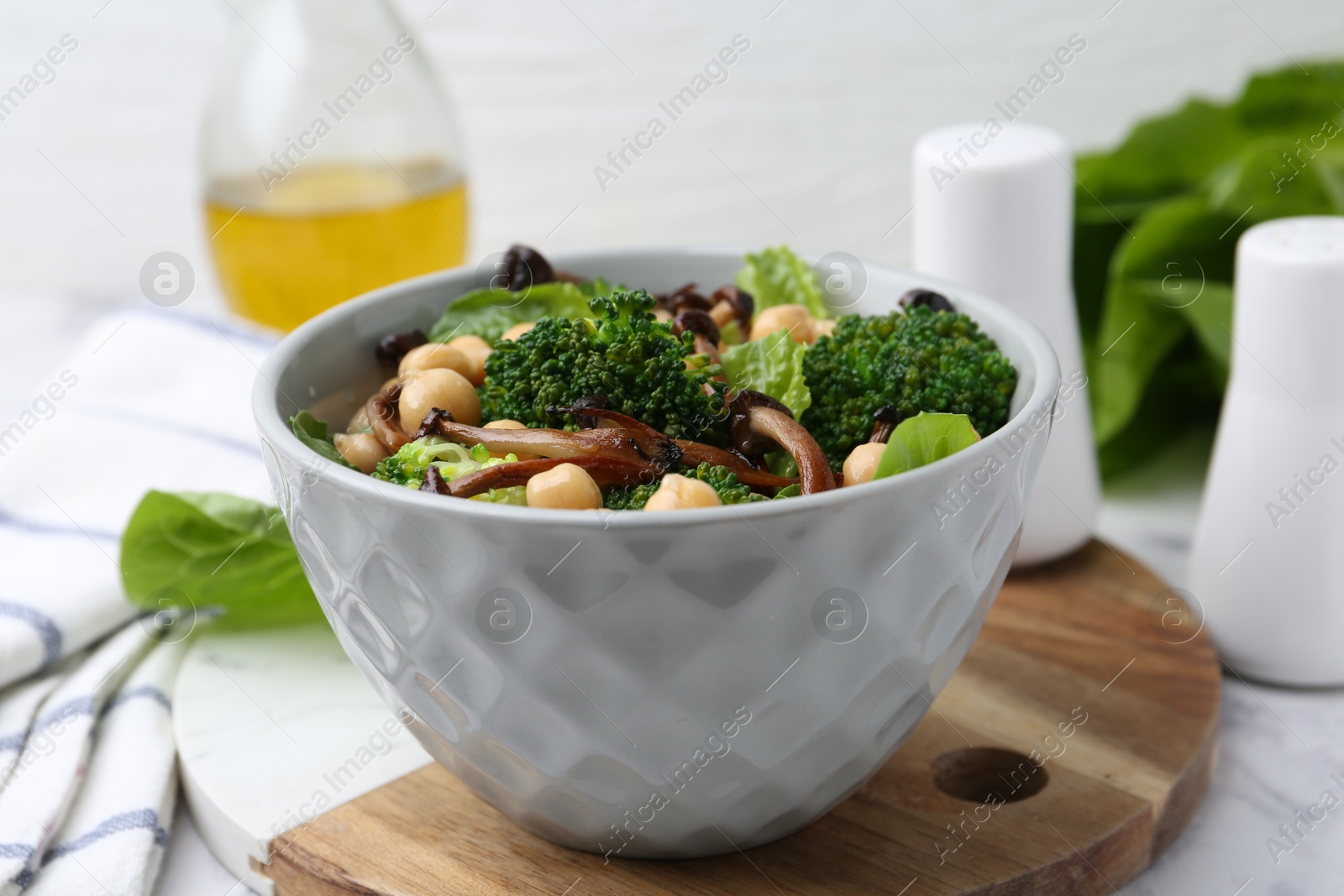 Delicious salad with shimeji mushrooms, chickpeas and broccoli in bowl on table, closeup Photo of Delicious salad with shimeji mushrooms, chickpeas and broccoli in bowl on table, closeup