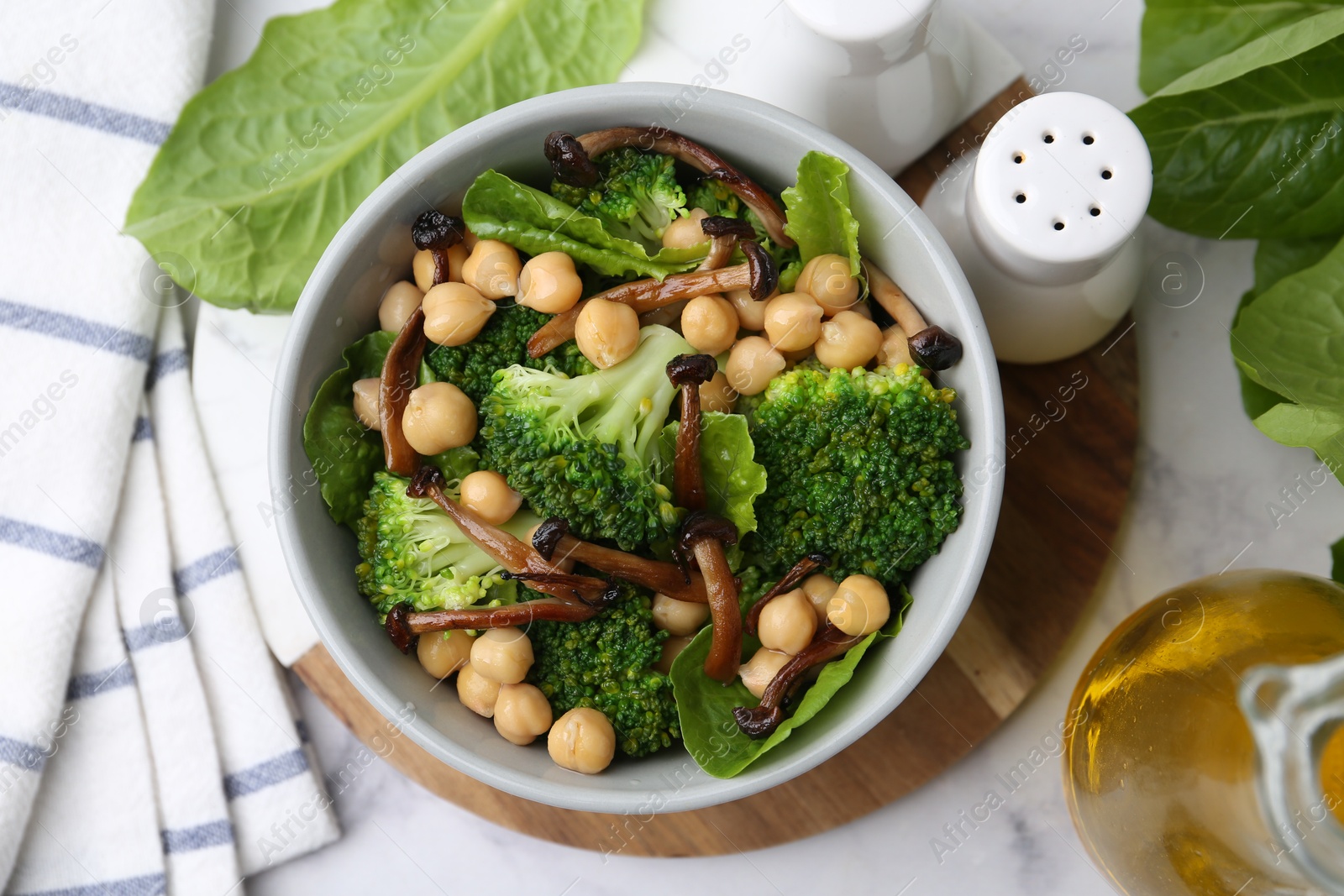 Photo of Delicious salad with shimeji mushrooms, chickpeas and broccoli in bowl on white marble table, flat lay