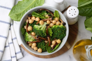 Photo of Delicious salad with shimeji mushrooms, chickpeas and broccoli in bowl on white marble table, flat lay