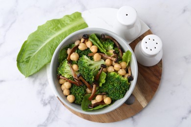 Photo of Delicious salad with shimeji mushrooms, chickpeas and broccoli in bowl on white marble table, top view