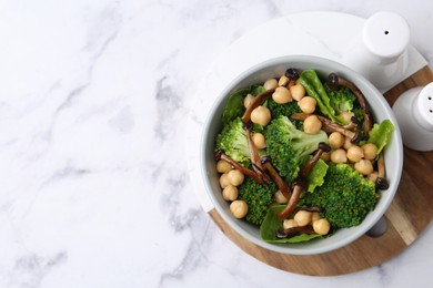 Photo of Delicious salad with shimeji mushrooms, chickpeas and broccoli in bowl on white marble table, top view. Space for text