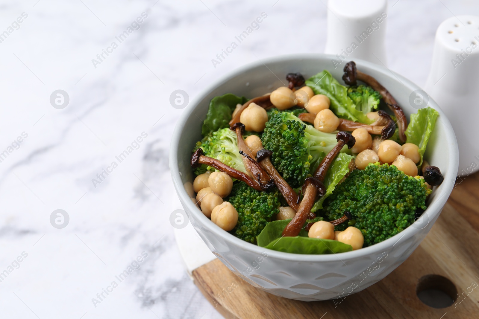 Delicious salad with shimeji mushrooms, chickpeas and broccoli in bowl on white marble table, closeup. Space for text Photo of Delicious salad with shimeji mushrooms, chickpeas and broccoli in bowl on white marble table, closeup. Space for text