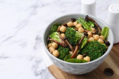Photo of Delicious salad with shimeji mushrooms, chickpeas and broccoli in bowl on white marble table, closeup. Space for text