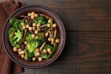 Photo of Delicious salad with shimeji mushrooms, chickpeas and broccoli in bowl on wooden table, top view. Space for text
