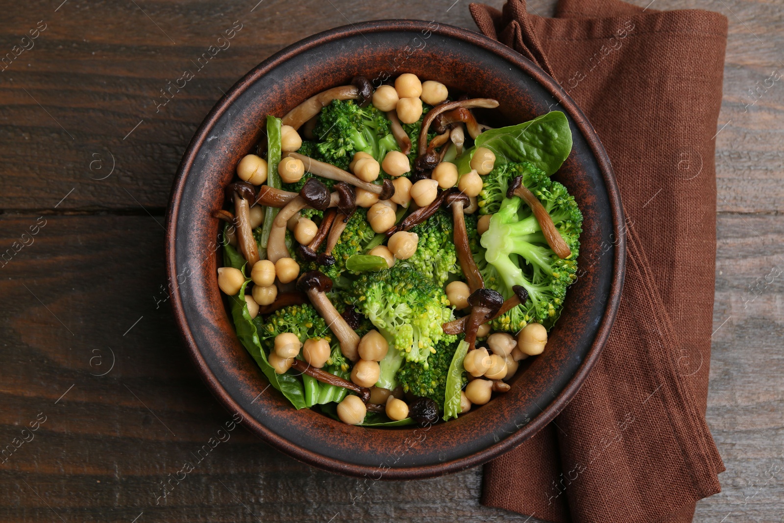 Delicious salad with shimeji mushrooms, chickpeas and broccoli in bowl on wooden table, top view Photo of Delicious salad with shimeji mushrooms, chickpeas and broccoli in bowl on wooden table, top view
