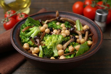 Photo of Delicious salad with shimeji mushrooms, chickpeas and broccoli served on wooden table, closeup