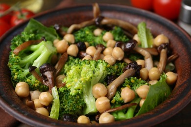 Photo of Delicious salad with shimeji mushrooms, chickpeas and broccoli in bowl on table, closeup
