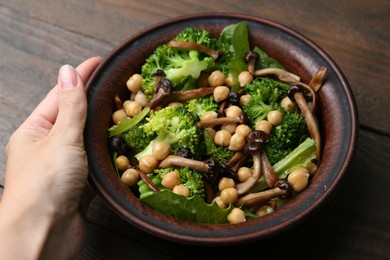 Photo of Woman with delicious salad with shimeji mushrooms at wooden table, closeup