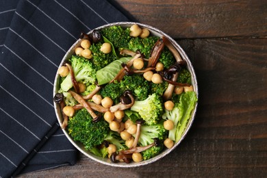 Photo of Delicious salad with shimeji mushrooms, chickpeas and broccoli in bowl on wooden table, top view