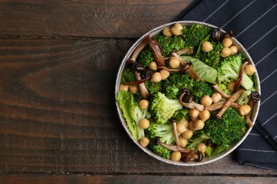 Photo of Delicious salad with shimeji mushrooms, chickpeas and broccoli in bowl on wooden table, top view. Space for text