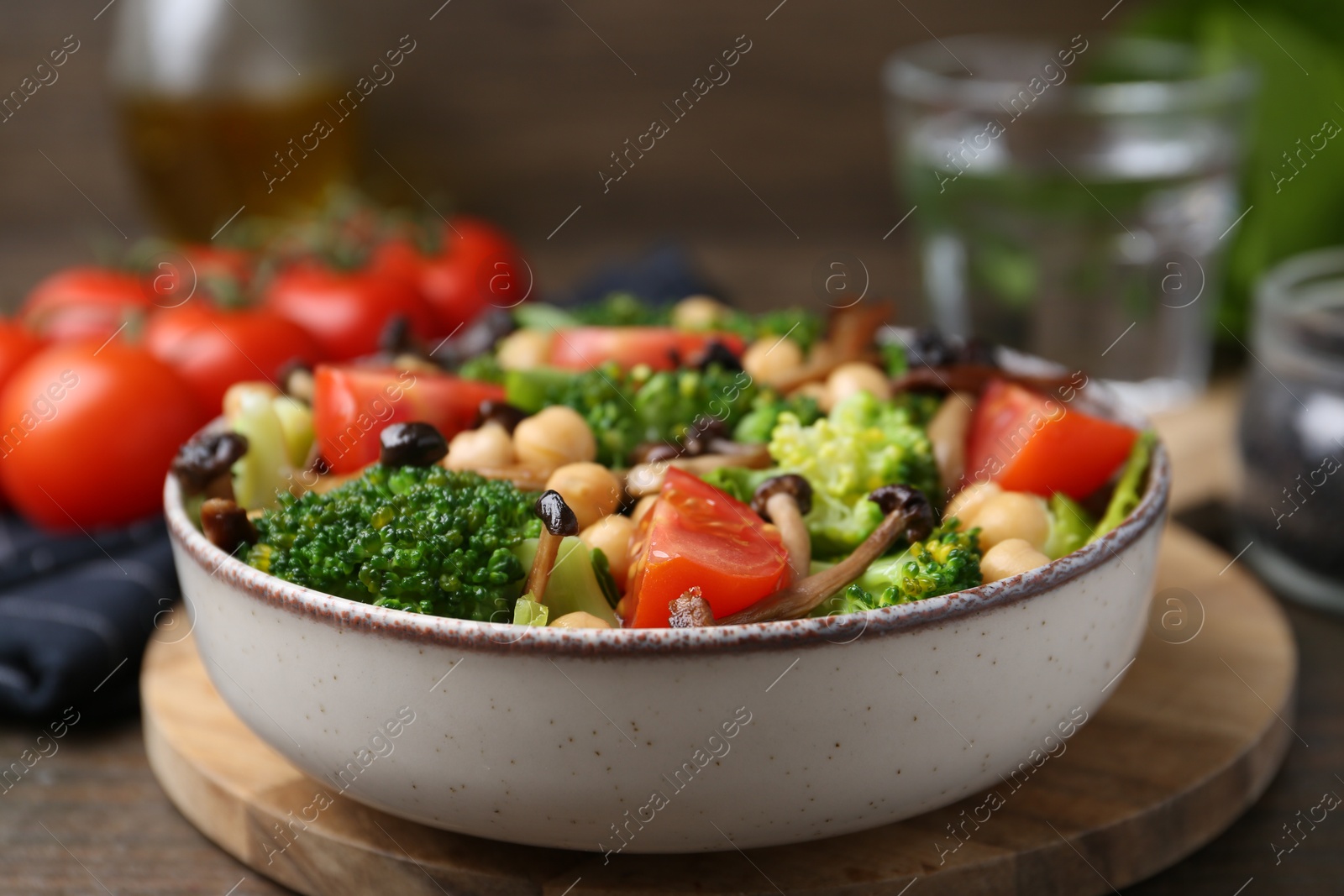Delicious salad with shimeji mushrooms, chickpeas, tomatoes and broccoli on table, closeup Photo of Delicious salad with shimeji mushrooms, chickpeas, tomatoes and broccoli on table, closeup