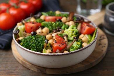 Photo of Delicious salad with shimeji mushrooms, chickpeas, tomatoes and broccoli on wooden table, closeup