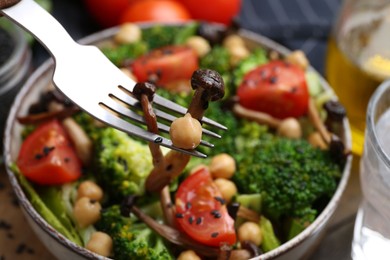 Photo of Eating delicious salad with shimeji mushrooms at table, closeup