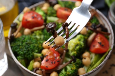 Photo of Eating delicious salad with shimeji mushrooms at table, closeup