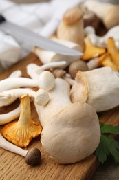 Photo of Different raw mushrooms and parsley on wooden table, closeup