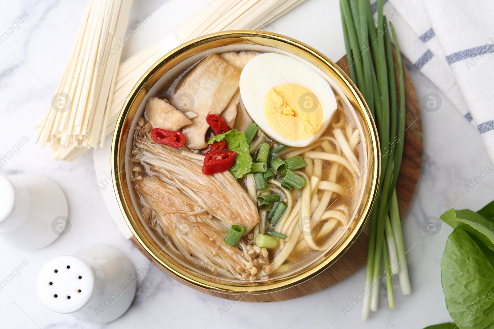 Tasty ramen with enoki and king oyster (eryngii) mushrooms on white marble table, flat lay Photo of Tasty ramen with enoki and king oyster (eryngii) mushrooms on white marble table, flat lay