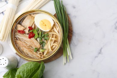 Photo of Tasty ramen with enoki and king oyster (eryngii) mushrooms on white marble table, flat lay. Space for text