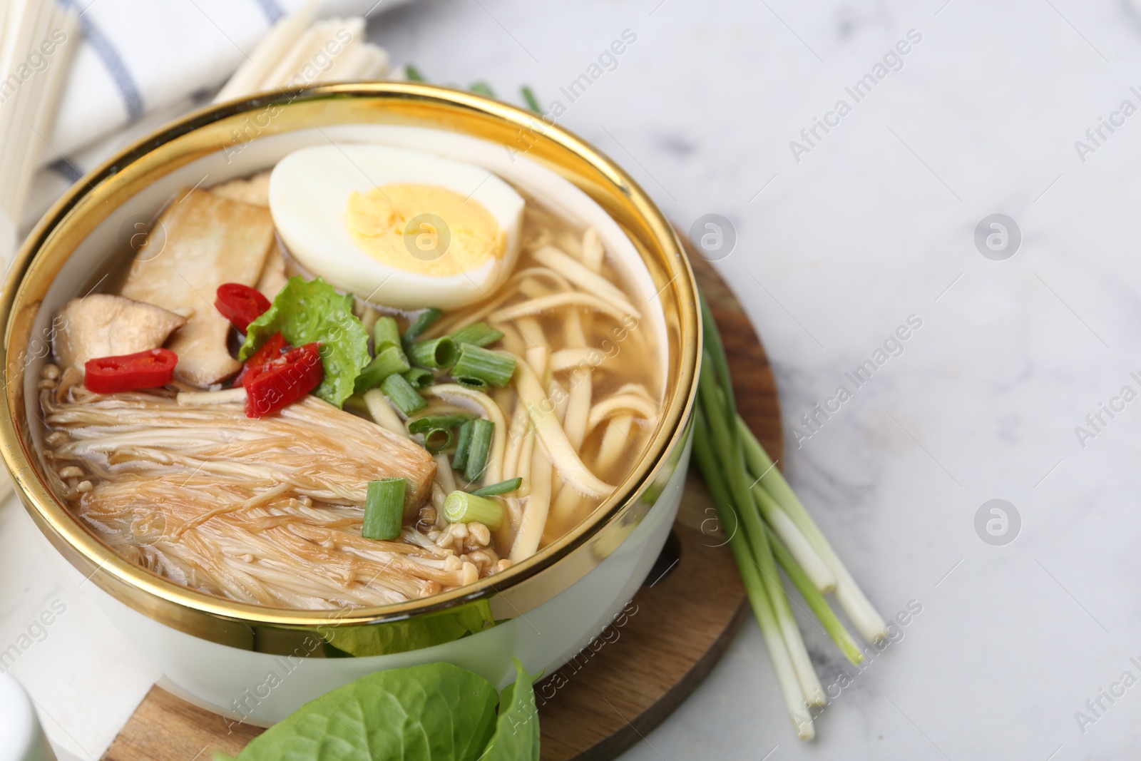 Tasty ramen with enoki and king oyster (eryngii) mushrooms on white marble table, closeup. Space for text Photo of Tasty ramen with enoki and king oyster (eryngii) mushrooms on white marble table, closeup. Space for text