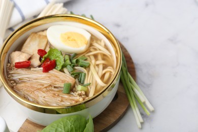 Photo of Tasty ramen with enoki and king oyster (eryngii) mushrooms on white marble table, closeup. Space for text