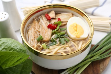 Photo of Tasty ramen with enoki and king oyster (eryngii) mushrooms on table, closeup